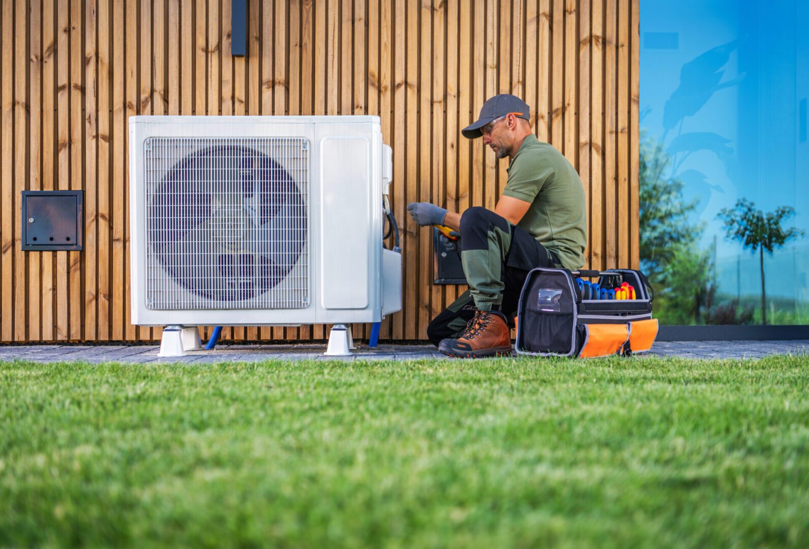 Technician repairing outdoor air conditioning unit with tools.