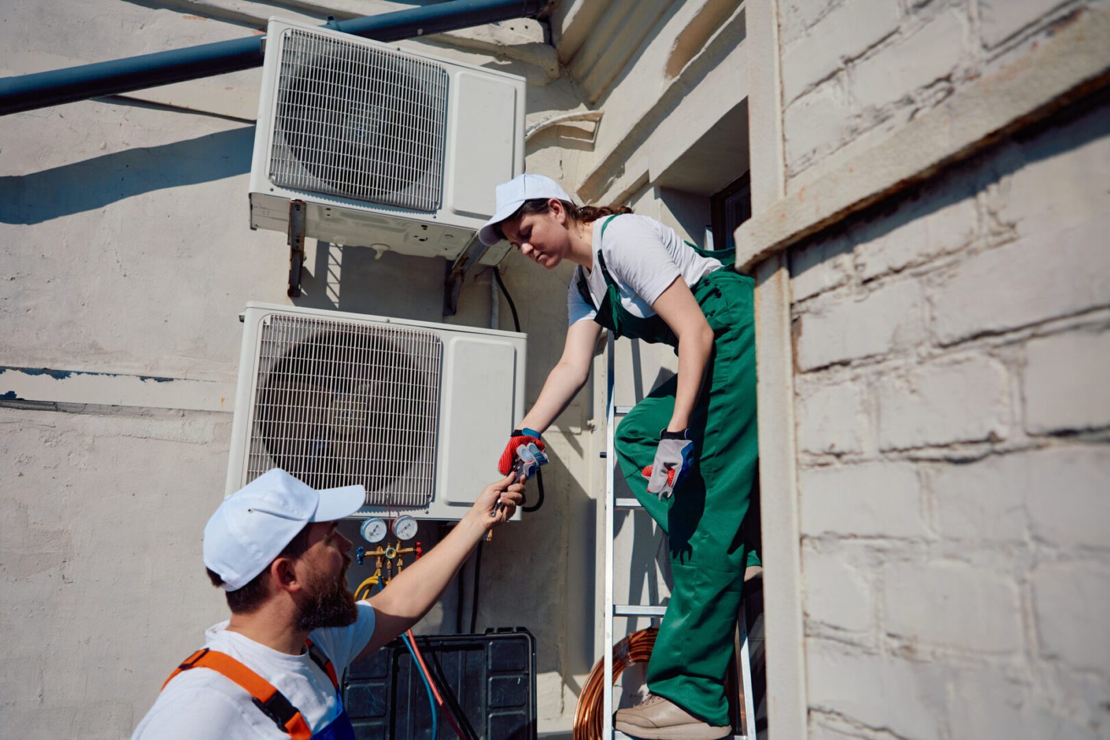 A technician shakes hands with a client outside a building near air conditioning units.