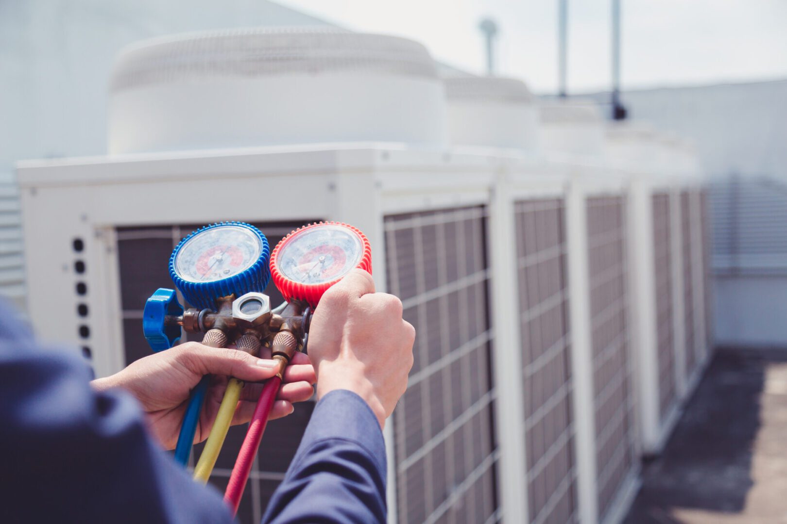 Technician adjusting HVAC gauges on air conditioning units.
